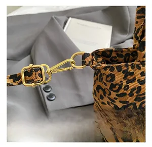 Detailed close-up of golden metal hooks and adjustable buckle on leopard print canvas bag