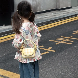 Rear view of child wearing yellow plaid mini bag with metal chain and top handle