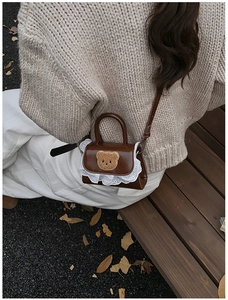Kids plush bear crossbody bag with lace trim shown on child model in autumn outdoor setting