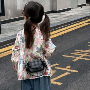 Outdoor shot of a kids plaid crossbody bag with black knot handle and silver chain strap