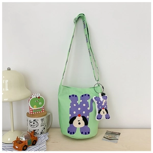 Detail of mint green canvas bucket bag with cartoon dog print and bone pendant accessory