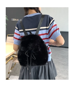 Furry black backpack with drawstring closure and soft texture shown on a female model