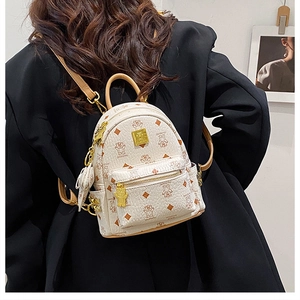 Dettaglio di zaino vintage beige con motivo a orsetto e logo dorato sulla modella