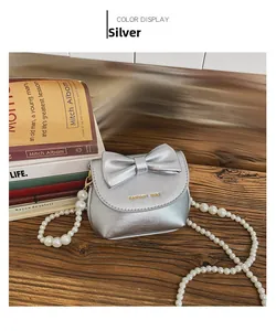 Close-up of silver mini handbag with metallic bow detail and pearl shoulder strap