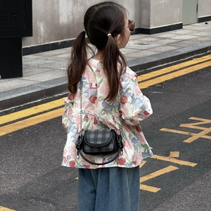 Outdoor street view of a girl wearing a black and grey plaid mini crossbody bag with knots