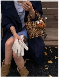 Détail d'un sac léopard avec pendentif chien et gants en tricot beige pour enfants