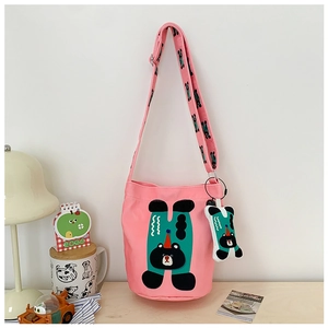 Detailed close-up of a pink canvas bucket bag with cartoon bear print and bear charm