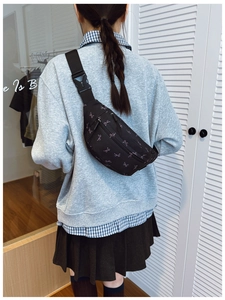 Close-up of a black canvas chest bag featuring pink bow prints and adjustable strap