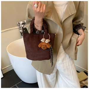 Gros plan d'un sac à main en daim marron foncé avec un joli pendentif ours en peluche