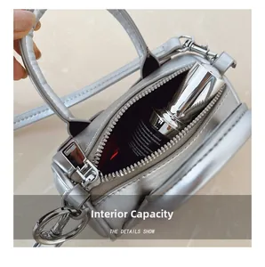 Detail view showing the internal capacity of a silver cylinder mini bag with shoulder strap