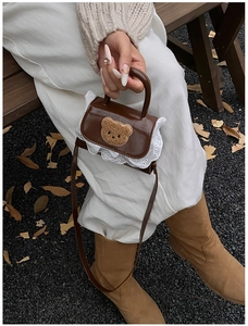 Detailed view of mini brown crossbody bag with plush bear patch and lace trim details