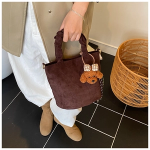 Détail du sac seau en daim avec poignée froncée et pendentif ours en peluche mignon
