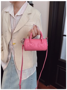 Detailed view of pink mini cylinder bag with embossed bows and adjustable strap for girls