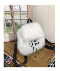 Detail of white faux fur backpack featuring plush texture and black drawstring closure