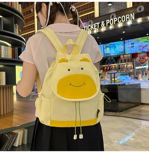 Détail du sac à dos jaune avec visage de dessin animé et oreilles 3D sur fond de cinéma