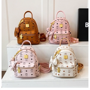 Dettaglio di mini zaini con texture in pelle, ciondoli a orsetto e loghi dorati