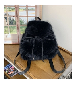 Detail of soft black faux fur texture and drawstring bow on a plush fashion backpack