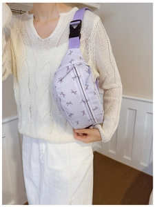 Close-up of lavender crossbody bag with bow print and adjustable buckle strap on model