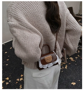 Détail d'un mini sac à main marron avec patch d'ours en peluche et bord en dentelle