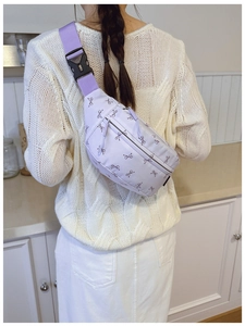 Back view of a light purple crossbody bag with bow pattern and adjustable strap on a model