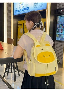 Vue latérale d'un sac à dos jaune de dessin animé porté par un mannequin en magasin