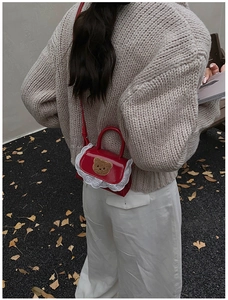Mini red crossbody bag with brown bear embroidery and white lace trim shown on child