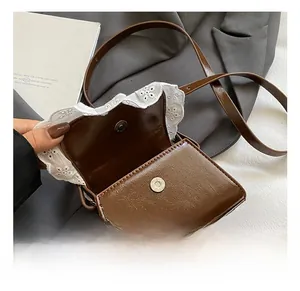 Gros plan sur un sac en cuir marron avec bordure en dentelle blanche et fermoir aimanté