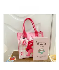 Detailed view of a pink checkered canvas tote bag with a cute red rabbit print and charm