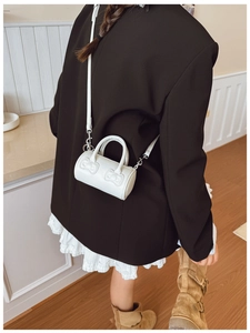 Detailed view of mini white cylindrical barrel bag featuring cute 3D bow decorations