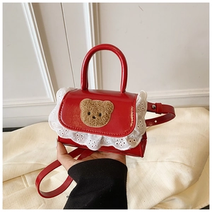 Detail of red kids handbag with cute plush bear embroidery and white lace trim edge