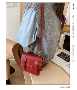 Detail view of burgundy leather messenger bag with gold clasp worn by child model