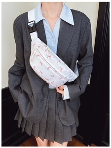 Close-up of white waist bag featuring red bow prints and adjustable shoulder strap