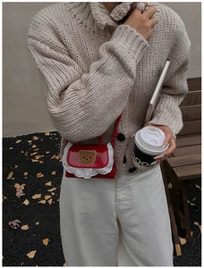 Détail du mini sac en cuir verni rouge avec patch ours en peluche et bordure en dentelle