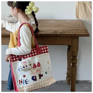 Detail of red checkered canvas tote bag for kids with cute cartoon illustration and charm