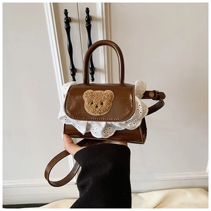 Detail of a brown faux leather mini bag with lace trim and a cute plush bear patch