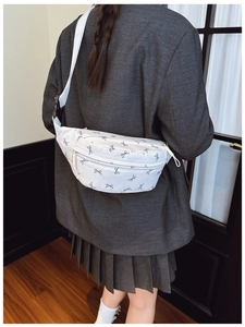 Detail of adjustable strap and buckle on white bow-print chest bag worn by a model