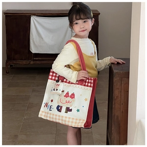 Close-up of kids canvas tote bag with cartoon monster print and matching charm accessory