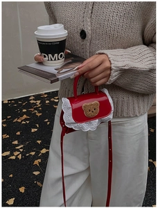 Détail du mini sac rouge avec bordure en dentelle blanche et écusson d'ours mignon