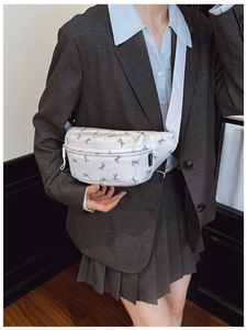 Close-up of white crossbody bag featuring bow print and blue nylon strap detail