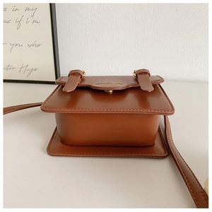 Detail shot of brown vintage satchel bag with gold buckles and glossy leather finish
