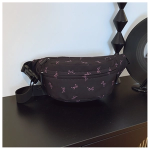 Detail of trendy black crossbody bag with pink bow prints and adjustable buckle strap