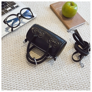 Detail of cute black mini barrel bag with dual bows and adjustable shoulder strap