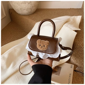 Détail du mini sac marron foncé avec broderie ours et bordure en dentelle blanche