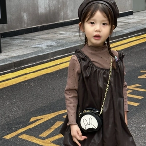 Detail of mini round bunny chain bag paired with a brown leather beret and toddler outfit