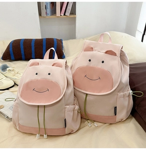Sac à dos vache rose mignon avec oreilles de dessin animé et cordon vert sur lit