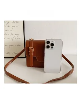 Brown leather messenger bag shown with a smartphone for real size comparison