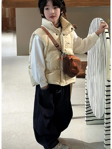 Kid wearing warm beige quilted puffer vest with white long sleeve top and crossbody bag