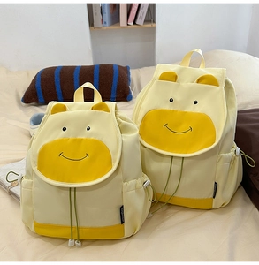 Détail de deux sacs à dos vache jaune en tailles large et petite sur un lit douillet