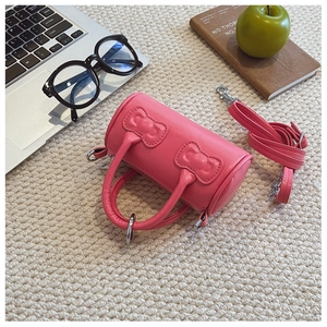 Pink cylinder bucket bag featuring 3D bow details and adjustable crossbody strap