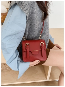 Detail of red messenger bag with golden buckles and fashion text on vintage leather